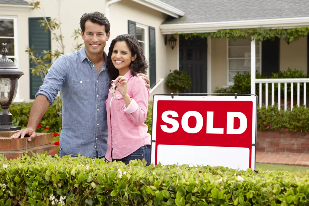 Hispanic Couple Outside Home With Sold Sign Hispanic Couple Outside Home With Sold Sign
