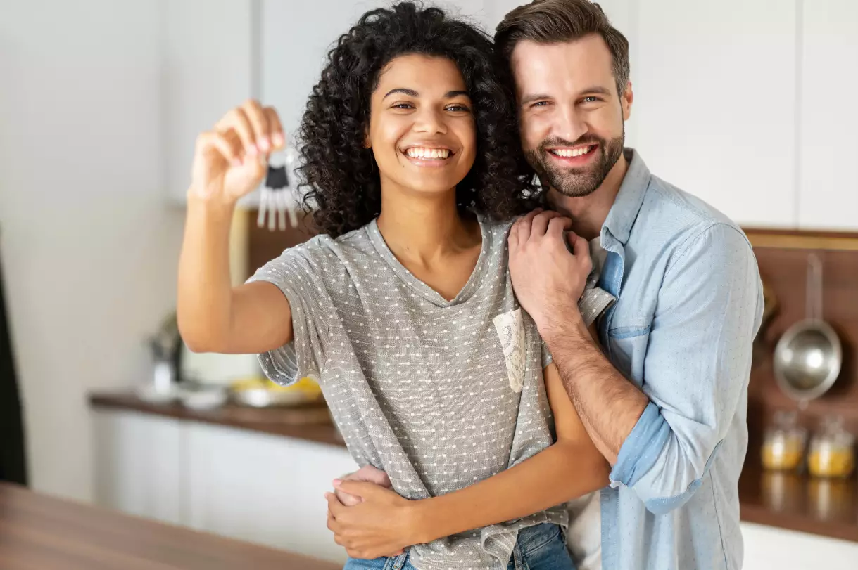 Cheerful young multi ethnic couple in love stand in embraces the kitchen, holding keys of a new house. Joyful international newlywed moved in new apartment, got a mortgage, moving day Cheerful young multi ethnic couple in love stand in embraces the kitchen, holding keys of a new house. Joyful international newlywed moved in new apartment, got a mortgage, moving day